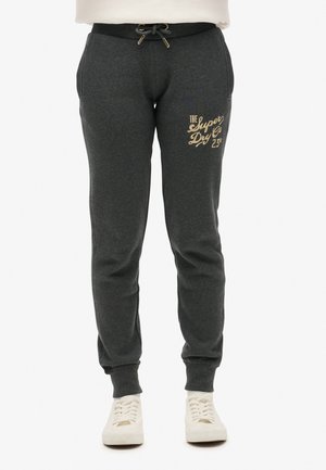 Grau-schwarze Jogginghosen aus weichem Material, mit einem Kordelzugbund, goldbedrucktem Logo auf dem Oberschenkel und gerippten Knöcheln.