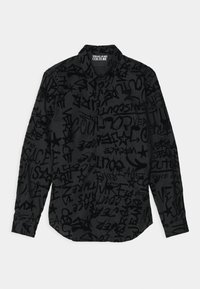 Camicia a maniche lunghe nera con un motivo grafico con testo e simboli astratti in diverse tonalità di nero e grigio.