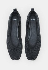 Čierne textúrované kožené balerínky s okrúhlymi štvorcovými špičkami a poutkami, označené "Bata pravá koža" vo vnútri.