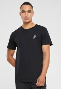 Black cotton T-shirt with short sleeves, round neckline, and small white graphic print on the left chest. Smooth texture, fitted design.