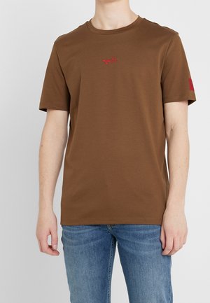 Brun bomulds t-shirt med korte ærmer, der har et lille rødt broderet logo på brystet og en rød detalje på ærmet.