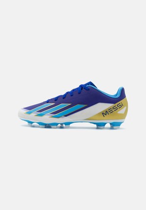 Botín de fútbol con una parte superior morada, acentos azules y un logotipo dorado. Presenta una superficie texturizada, seis tacos azules y un diseño aerodinámico.