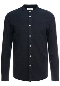 Camicia navy con colletto stand, caratterizzata da un motivo a pois, maniche lunghe e bottoni bianchi sul davanti. Tessuto morbido.