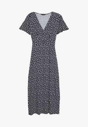 Robe navy à pois blancs, décolleté en V, manches flottantes et taille cintrée qui se prolonge en une jupe mi-longue en A.