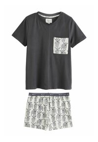 Grijze katoenen t-shirt met korte mouwen en een geborduurde zak, gecombineerd met crèmekleurige shorts met zwarte koeienillustraties en een marineblauwe tailleband.