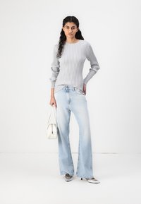 Szary prążkowany top z długim rękawem, jasnoniebieskie szerokie jeansy, srebrne buty na szpilce oraz biały torebka. Prosty, nowoczesny design.