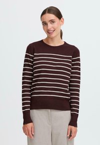 Bordeaux genser med kremfargede horisontale striper, rund hals, lange ermer og ribbestrikket kant. Mykt materiale, figurnær fasong, minimalistisk design.