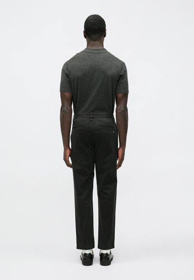 Črne bombažne hlače s prilegajočo obliko in zadnjimi žepi, kombinirane s temno sivo kratkoročno majico, pogled od zadaj.