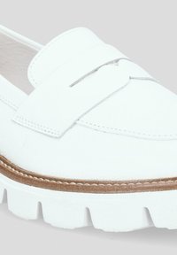 Białe skórzane mokasyny z zaokrąglonym noskiem, podniesionym paskiem z przodu i teksturowanym wykończeniem. Posiadają grubą białą gumową podeszwę i brązowe przeszycia.