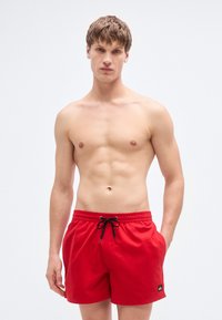 Κόκκινα μαγιό σορτς από ελαφρύ ύφασμα, με ελαστική μέση με μαύρο κορδόνι, πλαϊνές τσέπες και μικρό λογότυπο.
