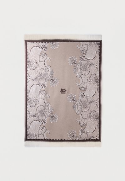 Tapis rectangulaire beige et marron avec des motifs floraux complexes le long des bords et des franges sur les côtés les plus courts.