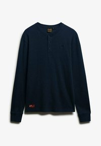 Marineblauwe langemouw Henley-shirt met drie-knopsluiting en klein rood merkembleem nabij de zoom.