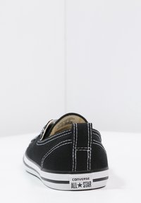 Černé plátěné tenisky s bílým prošíváním, gumovou podrážkou a štítkem "Converse All Star" na patě. Nízký střih s odolným materiálem.