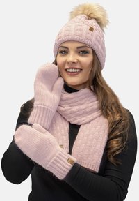 Gorro de punto rosa con pom-pom de pelaje sintético, bufanda con un patrón de canalé y manoplas a juego. Fabricado con material suave y cálido con detalles texturizados.