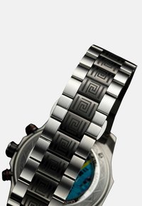 Stainless steel watch bracelet with a geometric pattern. Features a brushed finish and polished links. Distinct round watch face visible.
