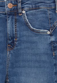 Donkere blauwe denim jeans met een lichte vervaging, voorzien van oranje stiksels, een metalen knoop en twee voorzakken met klinknagels.