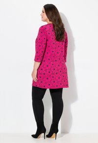 Pink tunika kjole med sort blomster mønster, 3/4 ærmer, parret med sorte leggings og ankelstøvler. Glat stof, knæ-længde design.