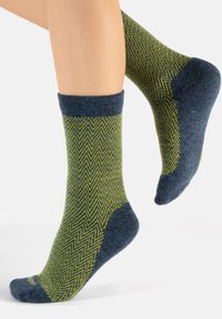 Calcetines de punto con un patrón de espina de pez verde, puño y puntera acanalados en navy, y un talón sólido en navy, mostrando un tejido texturizado.