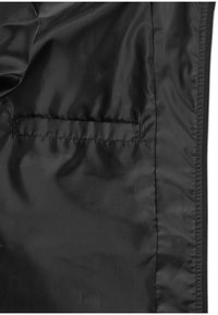 Intérieur de veste noire avec une poche passepoilée horizontale sur le côté gauche et une doublure en tissu lisse, légèrement brillante.