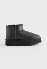 Schwarze Lederknöchelstiefel mit runder Zehenform, niedrigem Profil, weichem Innenfutter und strukturiertem Gummisohle. Schlaufe für einfachen Einstieg.