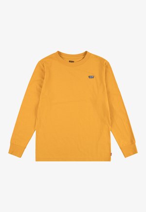 Camiseta amarilla mostaza de manga larga con cuello redondo, con pequeño logo de Levi’s en el pecho izquierdo y etiqueta en la costura lateral.