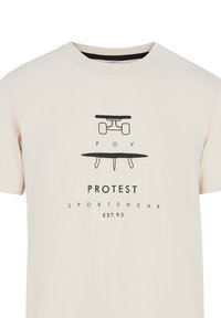 Šviesiai kreminis trumpomis rankovėmis marškinėliai, pagaminti iš medvilnės, su juodu grafikos dizainu vaizduojančiu riedlentę ir banglentę, teksto "PROTEST SPORTSWEAR EST.93".