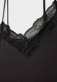 Camisole nera con scollatura a V decorata con delicati dettagli in pizzo, spalline sottili e una texture di tessuto liscia.