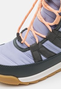 Scarpa viola imbottita con accenti grigi, dotata di cinturini texturizzati, lacci arancioni e un'intersuola bianca. Suola in gomma con motivo antiscivolo.