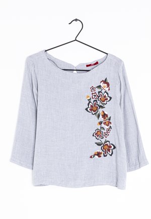 Gray, lightweight top with three-quarter sleeves, featuring floral embroidery in red, orange, and green on the left side. Keyhole neckline.