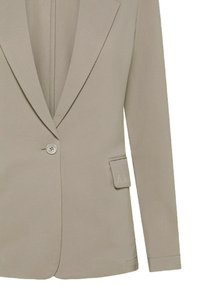 Blazer beige chiaro con finitura testurizzata, dotato di revers a punta, chiusura con un solo bottone e una piccola tasca con dettaglio del logo.