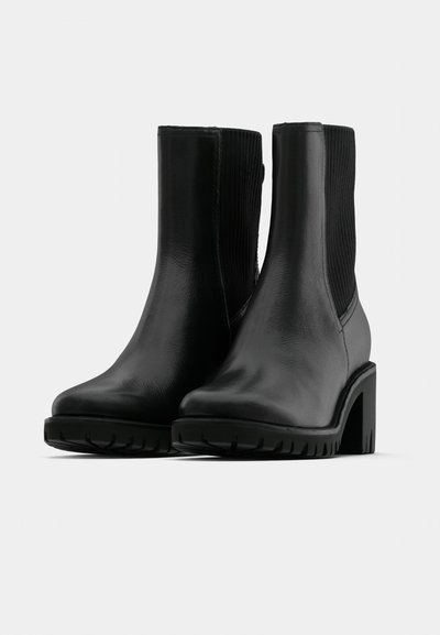 Bottes noires pour la cheville avec une finition en cuir lisse, côtés élastiques côtelés, talons en caoutchouc épais et semelles extérieures texturées pour une meilleure adhérence.