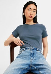 Slate blue, figurerad t-shirt med rund halsringning, parat med högmidjade ljusa denimjeans med en urtvättad look och klassiska fickor.