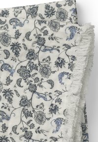 Bomuldsstof med lyse beige baggrund og indviklede mønstre i mørkeblå blomster og paisley, prydet med lyseblå detaljer og frynsede kanter.