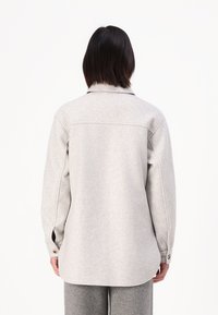 Giacca camicia tessuta grigia chiara con colletto, polsini con bottone e orlo arrotondato. Presenta una texture morbida e una vestibilità classica.