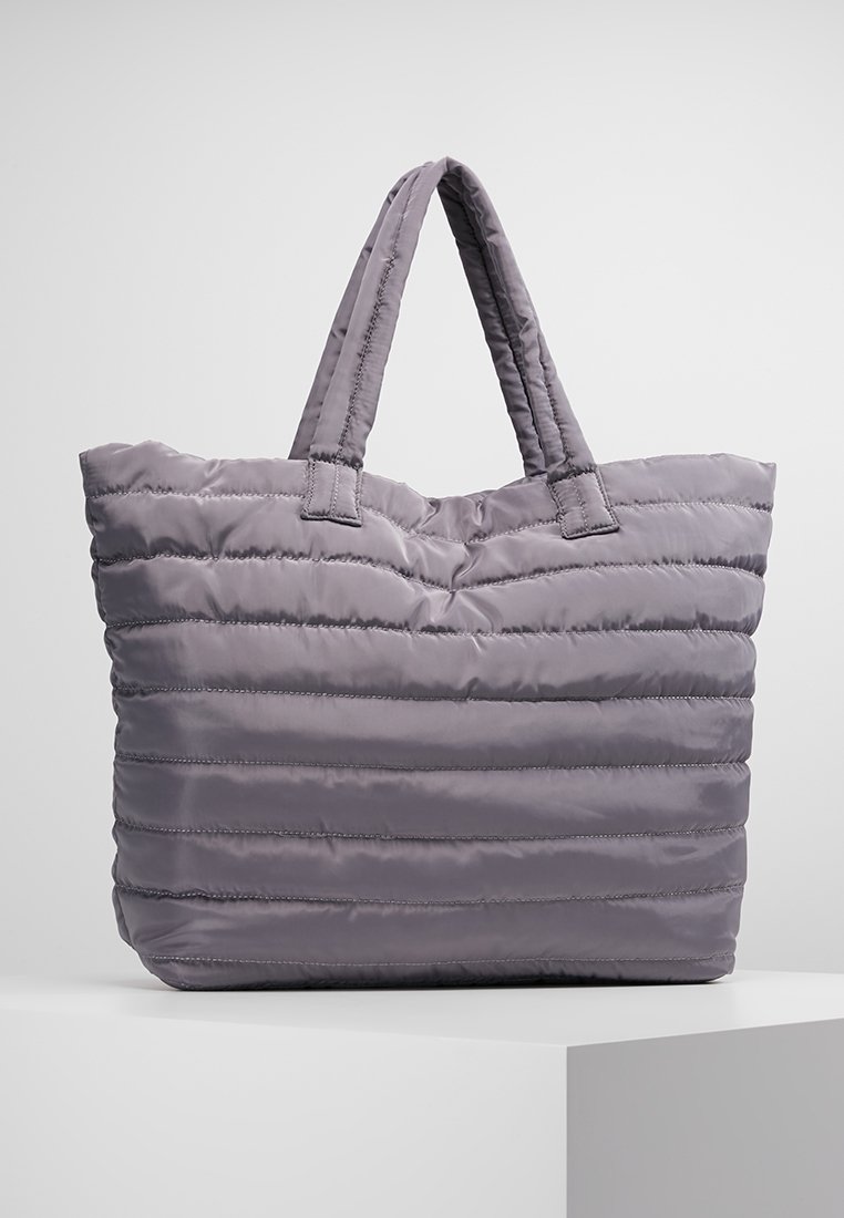 Lavender quilted tote bag with two padded handles, displayed upright on a white surface against a plain background.