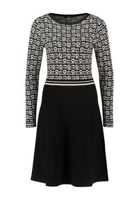 Robe blanche et noire à manches longues avec un haut à motifs présentant un texte vertical répété et une jupe noire évasée unie.