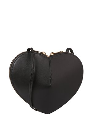 Schwarze herzförmige Umhängetasche aus Leder mit goldfarbenem Reißverschluss und dünnem Schulterriemen auf weißem Hintergrund.