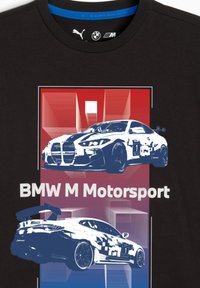 T-shirt noir avec des graphiques stylisés en bleu et blanc de deux voitures de course BMW sur un fond rouge et violet. Le texte indique "BMW M Motorsport."