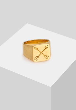 Gold metal signet ring with a square face, featuring an engraved crossed arrows design. Smooth finish, wide band.