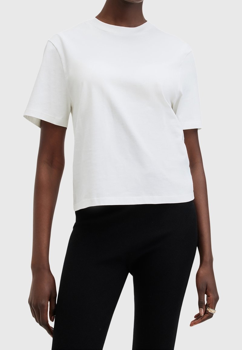 Bílý, krátký rukáv tričko vyrobené z bavlny s kulatým výstřihem a uvolněným střihem, v kombinaci s černými žebrovanými elastickými kalhotami.