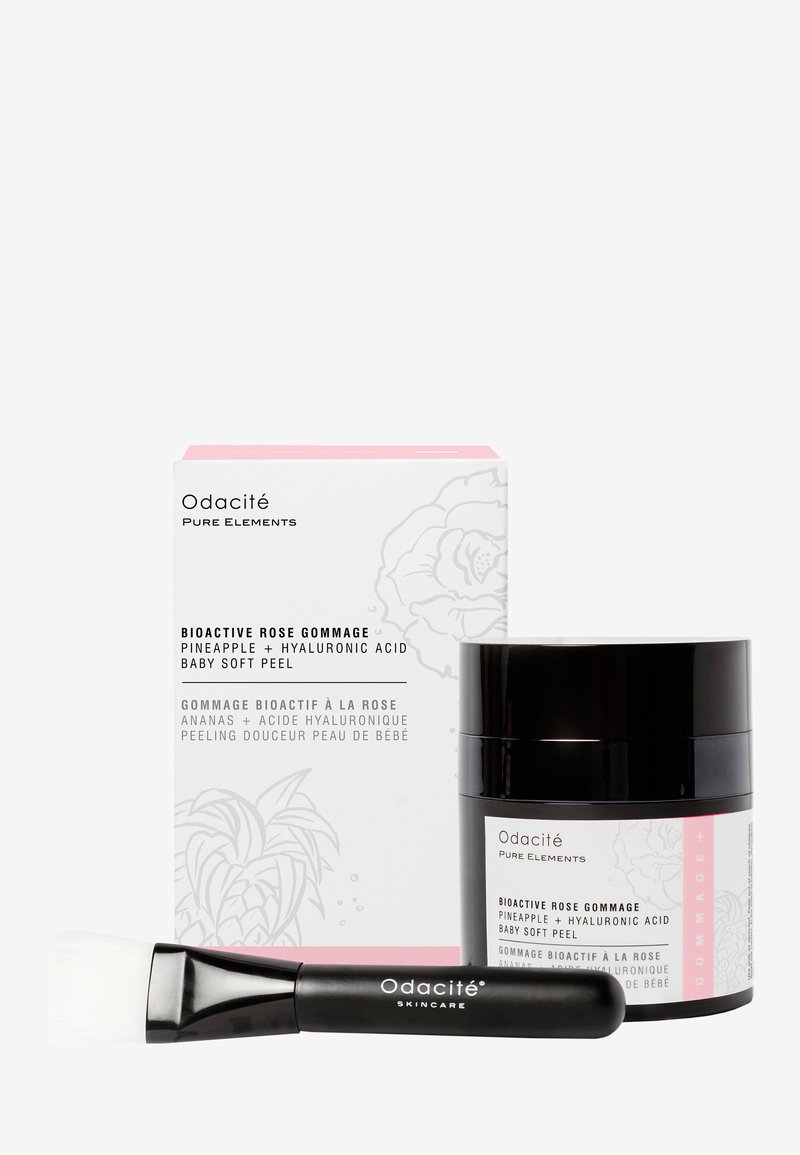 Le set Odacité Bioactive Rose Gommage comprend un pot noir avec une étiquette rose, un emballage blanc avec un design floral et un applicateur en brosse noir.