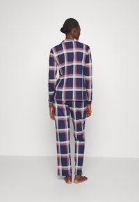 Marineblauw en witte geruite pyjama set, met lange mouwen en broek, gemaakt van zachte stof met een relaxte pasvorm en kraag met knopen.