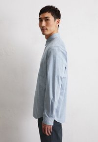 Light blue checkered shirt, long sleeves, button-down collar, single chest pocket, and button cuffs. Material appears soft and lightweight.