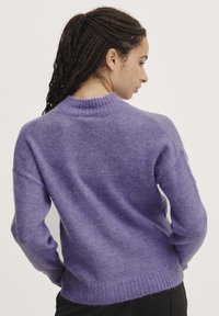 Lilla strikket sweater med rund hals, lange ærmer og ribbet kant. Blød tekstur med en let løs pasform, der viser et enkelt design.