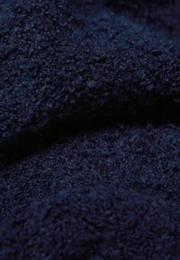 Marineblauer, strukturierter Stoff mit weichem, flauschigem Aussehen und unebener Oberfläche, ideal für Wärme und Komfort.