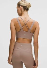 Brassière de sport rose clair avec une texture côtelée et des bretelles croisées, associée à un legging taille haute assorti avec des accents subtils.