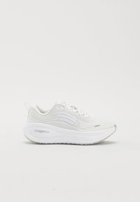 Chaussure de course Nike ZoomX blanche avec tige texturée, semelle épaisse amortie et design à lacets sur un fond clair uni.