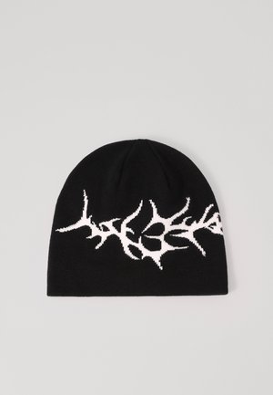 Knit beanie hat in black with a white abstract design resembling branches or coral. Soft texture, rounded crown, and snug fit.
