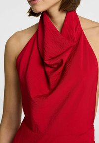 Top rosso con scollo all'americana, caratterizzato da un design drappeggiato e testurizzato con morbide pieghe e una finitura liscia, che mette in risalto una silhouette aderente.