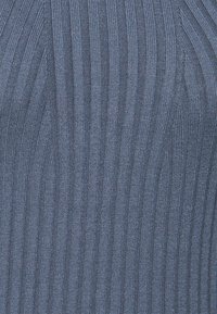 Blå ribbad stickad tyg med vertikala texturerade linjer och lätt diagonala mönster som är vävda genom hela.